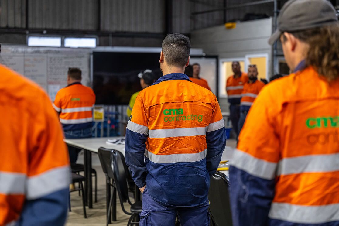 A man facing away from camera. He is wearing hi-vis CMA Contracting branded work wear